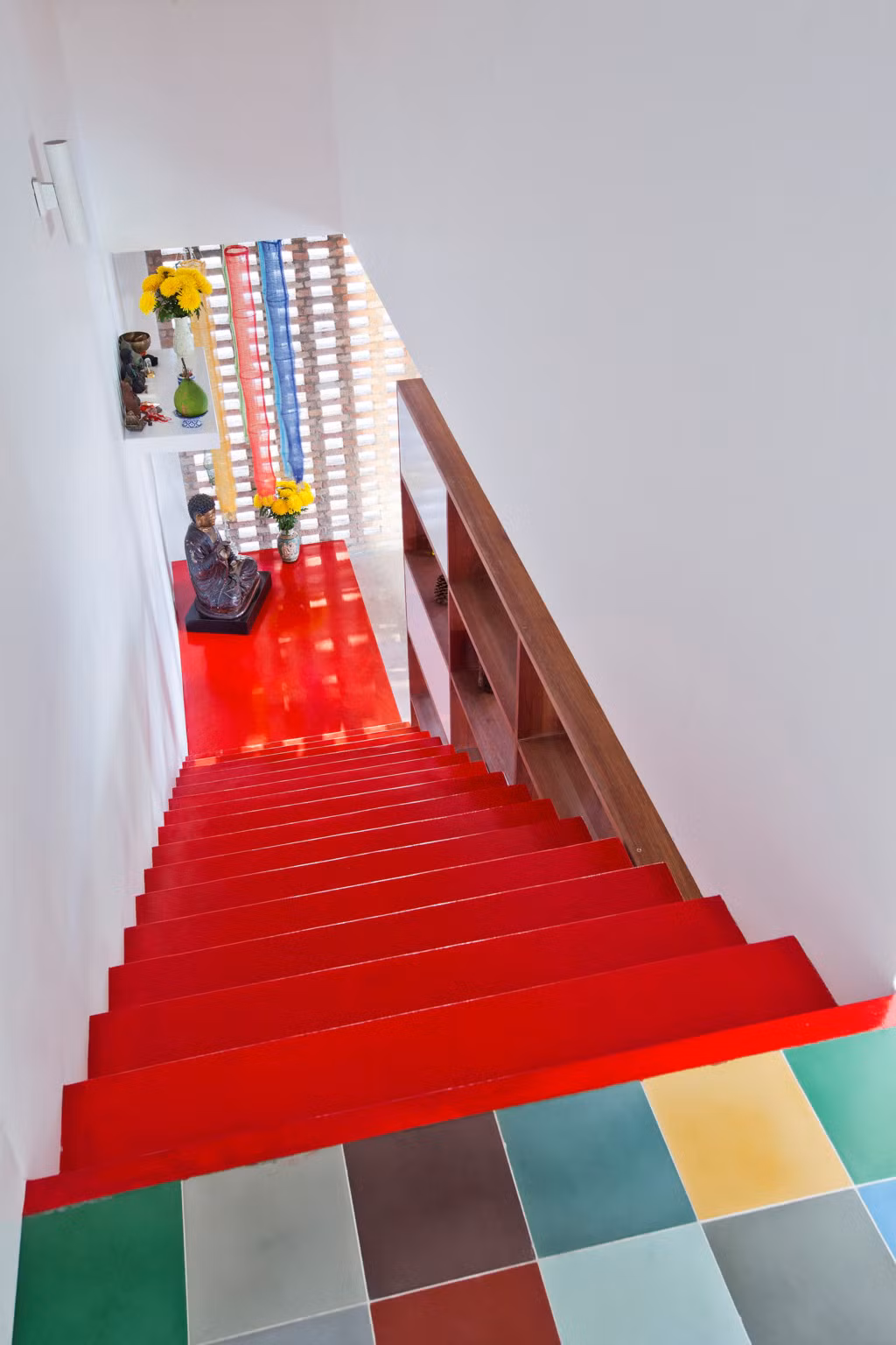 Cầu thang màu đỏ tươi nối từ phòng khách tầng hai lên tầng áp mái.