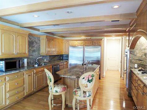 Phòng bếp cổ điển với hệ thống tủ bếp bằng gỗ sáng màu và đảo bếp lát đá hoa cương.