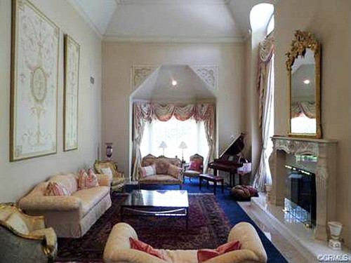 Phòng khách rộng rãi đậm phong cách Châu Âu của thế kỷ trước với những bộ salon kiểu dáng quý tộc, cửa sổ cao hình vòm, rèm cửa cầu kỳ và trang trí thêm chiếc gương với phần khung mạ vàng đặt phía trên lò sưởi ốp đá trắng.