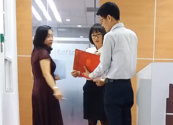 Nhân viên công ty xổ số và đại diện ngân hàng làm thủ tục chuyển tiền cho ông H.V.T. Ảnh: Việt Tường.