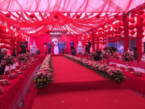 Phần cổng chào được thiết kế dạng mái vòm, trang trí bằng nhiều hình trái tim thực sự hoành tráng và ấn tượng. Phông nền đám cưới tràn ngập một màu đỏ rực rỡ, bên cạnh đó là vô số đèn, hoa tạo ra cảnh tượng lung linh huyền ảo khiến người nhìn không rời mắt. Không chỉ gây ấn tượng bằng cách trang trí, đám cưới còn khiến người ta ngạc nhiên vì những thông tin liên quan tới số lượng khách mời, mâm cỗ bày biện. Chưa kể, theo lời đồn đám cưới còn được tổ chức suốt 5 ngày với hàng nghìn vị khách tới tham dự.