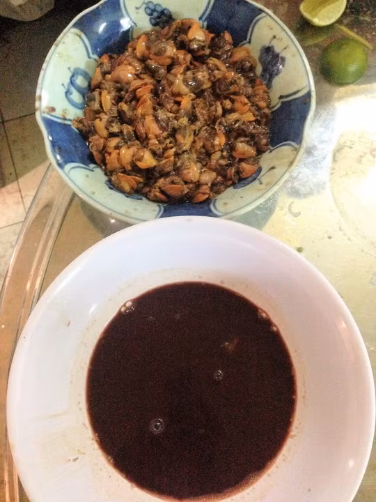 - Nêm vào chén tiết sò huyết 1 muỗng cà phê bọt ngọt, đánh cho tan đều. - Phần thịt sò huyết còn lại vắt vào nửa trái chanh, mù tạt, ½ rau húng lũi xắt nhuyễn. Dùng đũa trộn đều cho thịt sò thấm gia vị.