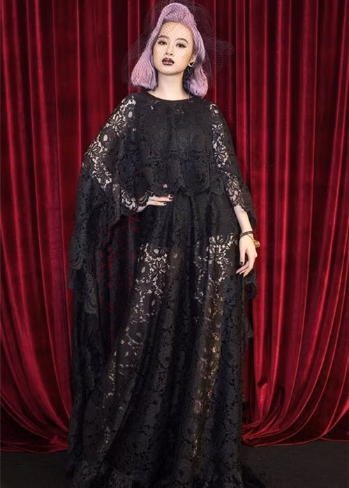 Tại show diễn mới nhất của NTK Đỗ Mạnh Cường, người đẹp Angela Phương Trinh đã áp đảo dàn sao lớn bé với bộ cánh tuyền đen theo dresscode của sự kiện. Người đẹp đã tự cộng cho mình cả chục tuổi khi diện thiết kế ren rườm rà, kết hợp với mái tóc hồng và lối trang điểm môi thâm như ma nữ.