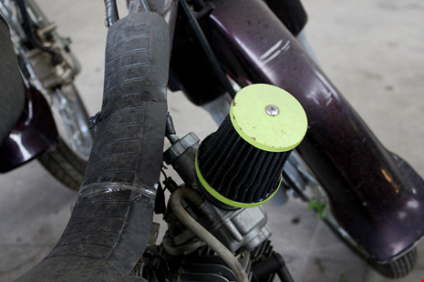 Một chiếc dream cũ được gắn thêm một bộ phận có hình trụ màu xanh gọi là Pô e. Ảnh: LÊ THOA