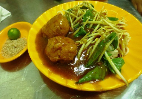 Đĩa bánh tằm được chan nước cà ri gà thêm phần thịt, mề và huyết được băm nhỏ chan lên ăn kèm với rau sống.