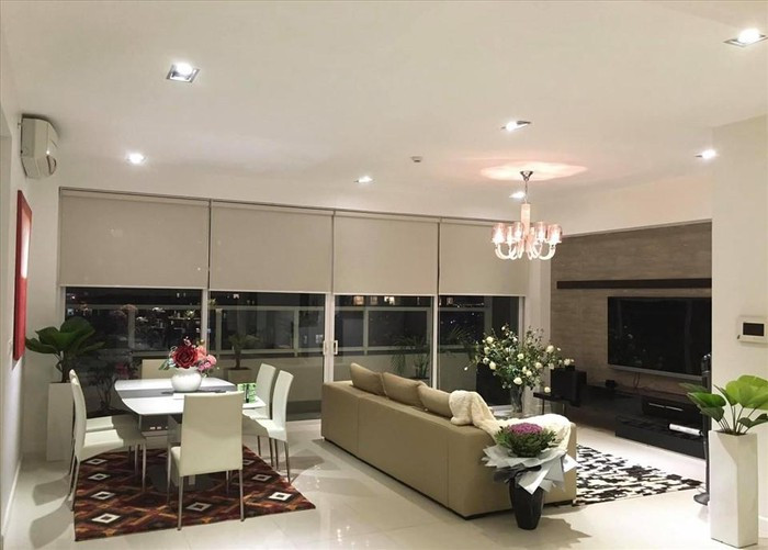 Phòng khách có đèn chùm sang trọng, sofa tông trầm dài và một chiếc tivi cỡ lớn.