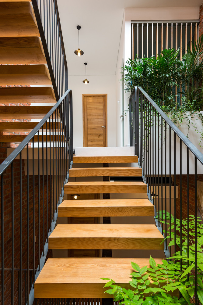 Bậc thang gỗ với kết cấu thép, hành lang trước phòng bằng lam gỗ, gạch đỏ cho toàn bộ tường khu vực thông tầng.
