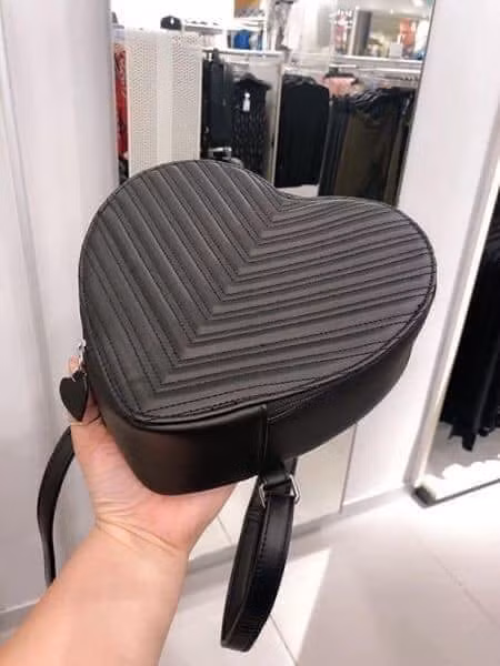 Balo có tay cầm, bên trên có khóa kéo hình tim, cùng dây đeo vai có thể điều chỉnh.