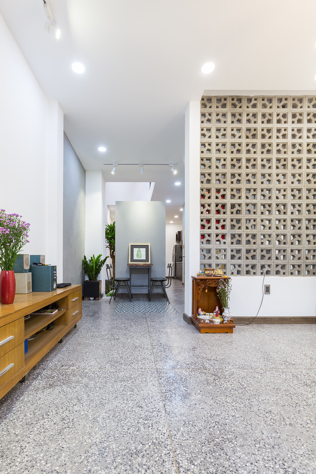 Những bức tường bằng gạch bông gió ngăn cách phòng khách nơi tầng trệt với khu vực thông tầng cũng góp phần làm nên màn hoa nắng cho phòng khách.