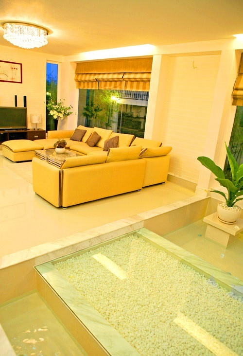 Lối dẫn vào phòng khách ốp kính trong suốt, có sỏi đá màu trắng ở giữa và hai hồ nước ở hai bên. Ảnh: FBNV.