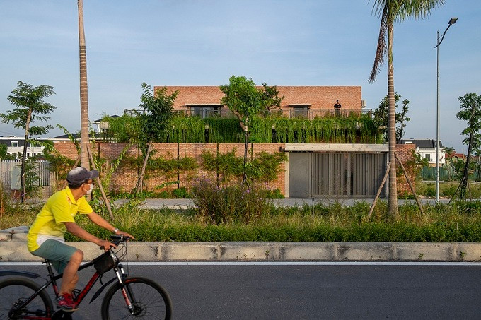 Nhìn từ bên ngoài, ngôi nhà (Mạo Khê, Quảng Ninh) nổi bật với màu đỏ của gạch và màu xanh của cây cối. Ảnh: Đức Nguyễn.