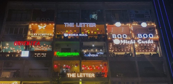 Vào buổi tối, bên ngoài tòa chung cư rực rỡ sắc màu với rất nhiều biển hiệu. Ảnh: Tiền phong.