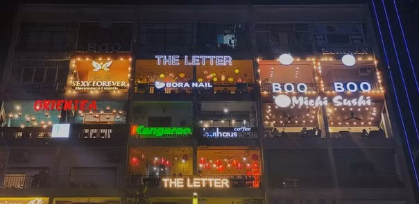 Vào buổi tối, bên ngoài tòa chung cư rực rỡ sắc màu với rất nhiều biển hiệu. Ảnh: Tiền phong.