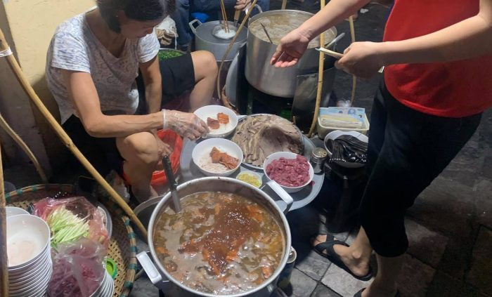 Nằm khuất trên vỉa hè ngay ngã tư Hàng Đường giao với Hàng Chiếu, quán ăn này không có biển hiệu hoành tráng, chỉ độ chục bộ bàn ghế nhựa xanh dưới ánh đèn đêm le lói. Ảnh: vietnamnet