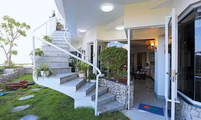 Tầng dưới gồm hai căn hộ và sân vườn kết nối với tầng trên qua một cầu thang lộ thiên. Ảnh: CL&amp;XH.