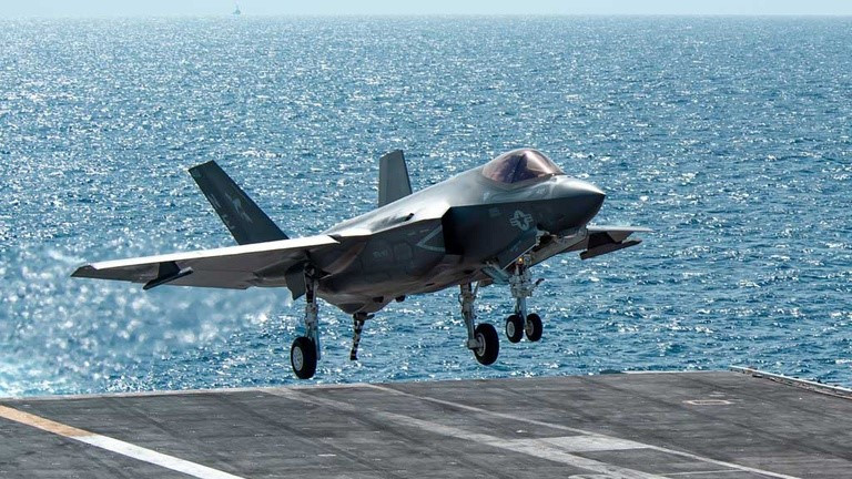 Cận cảnh một tiêm kích hạm F-35C hạ cánh với móc cáp hãm đà ở đuôi máy bay đã được bung ra, có thể thấy càng trước của máy bay sử dụng bánh kép, trong khi các phiên bản khác của F-35, chỉ sử dụng một bánh đơn.