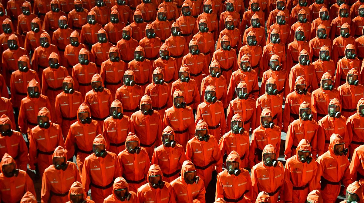 Khối duyệt binh mặc đồ bảo hộ màu cam và đeo mặt nạ phòng độc, đại diện cho nỗ lực chống Covid-19 ở Triều Tiên.