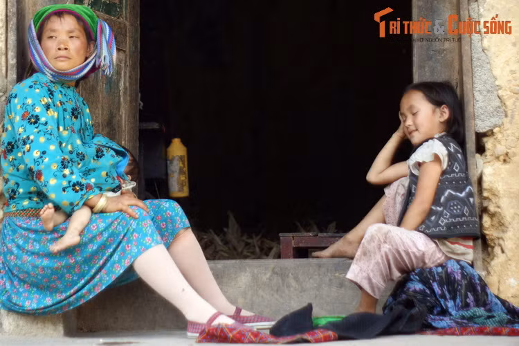 Ba mẹ con bên bậc cửa của ngôi nhà trình tường cũ xưa.