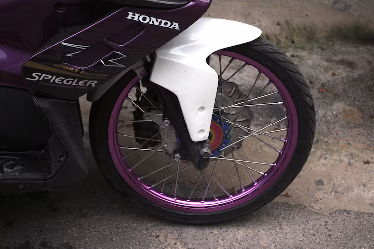 Chi tiết mang tính quyết định để khiến Air Blade mang phong cách xe đua drag đó là cặp bánh xe đã được chuyển sang bánh căm có đường kính 17 inch như xe số phổ thông, đi kèm với lốp mỏng 60/90/17 chống cản gió cùng niềng nhôm và moay-ơ màu tím nổi bật. Hệ thống phanh cũng được nâng cấp nhẹ với đĩa hoa đồ chơi và heo Nissin.