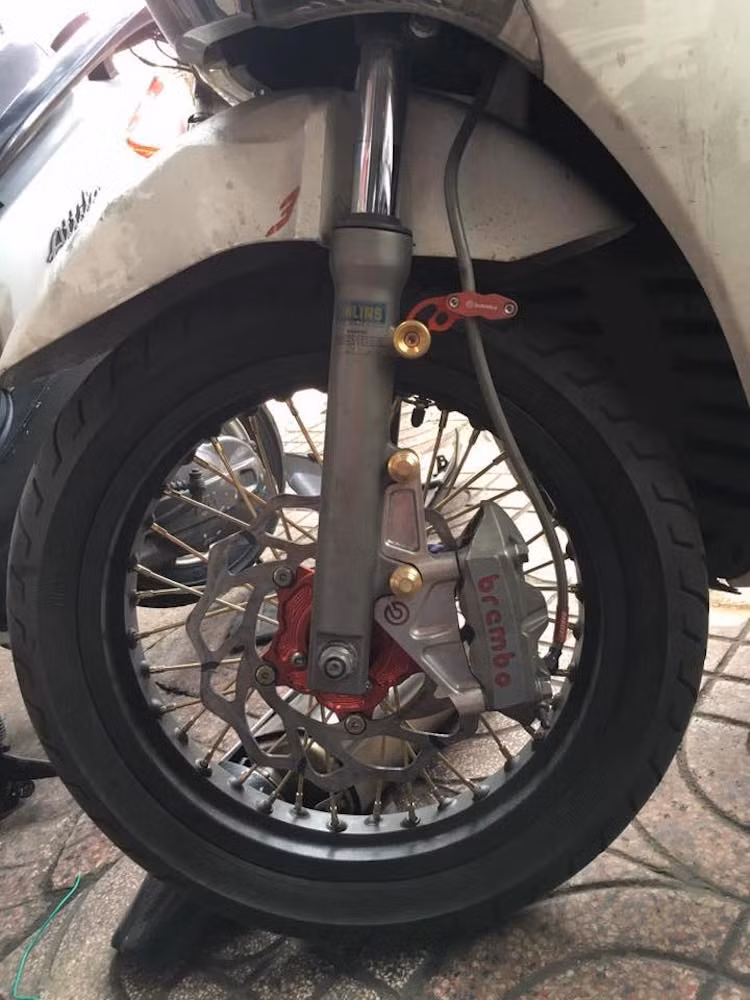 Với cặp bánh căm vàng và niềng đen mờ, chiếc xe không chỉ trở nên "ngầu" mà còn trở nên độc đáo và êm hơn, do bánh căm tán rung động từ mặt đường tốt hơn vành đúc. Chưa dừng lại ở đó, hệ thống phanh trước của xe còn được độ lại với heo Brembo M4 pát CNC "hàng thửa" và đĩa hoa lòng CNC.