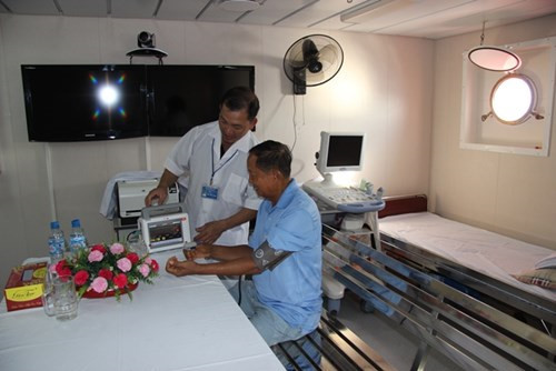 Trong ảnh, bác sĩ Thái Đàm Lương (áo trắng), người có trên 20 năm kinh nghiệm công tác trong ngành quân y đang đo huyết áp cho một bệnh nhân cao tuổi trên tàu 561.