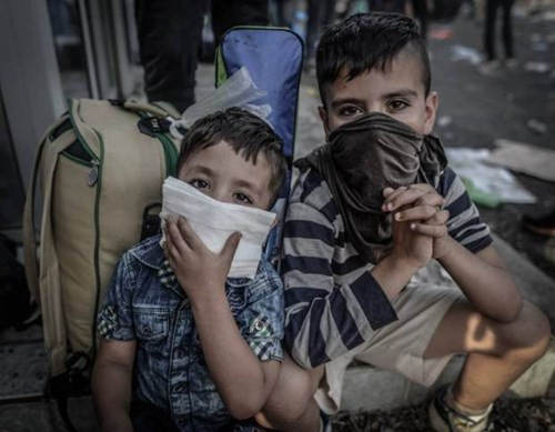  Hai đứa trẻ nhập cư che mặt ngăn hơi cay của cảnh sát