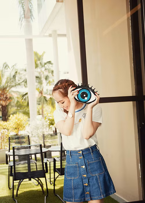 Lựa chọn phong cách thời trang Hàn Quốc, Quỳnh Nga kết hợp trang phục với túi hình con mắt ngộ nghĩnh. 