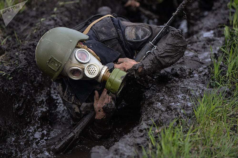 Trong khi đó bò trên bãi bùn lấy họ phải đeo mặt nạ phòng độc để tăng độ khó cho bài kiểm tra. Nguồn ảnh: Sputnik.