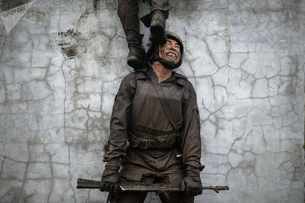 Hỗ trợ đồng đội vượt qua chướng ngại vật với tấm thân nặng nề đầy bùn đất. Nguồn ảnh: Sputnik.