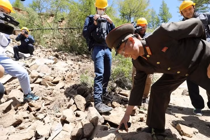 Một quan chức Triều Tiên đang chỉ tay vào đống đá trong lúc ông giải thích với các nhà báo sau khi đường hầm thứ 2 bị nổ phá hủy.