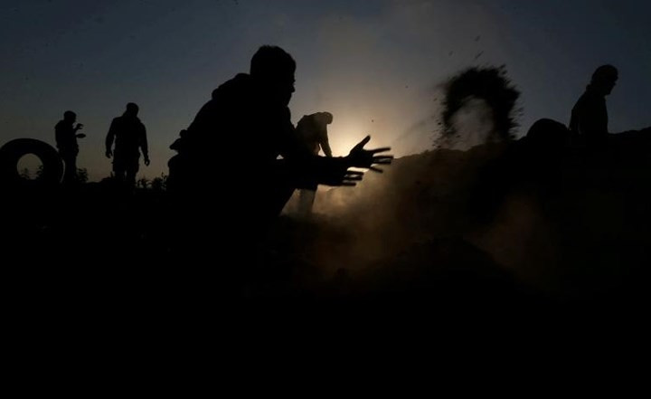 Người Palestine đang cố dập lửa gây ra bởi các vật thể mà máy bay không người lái Israel thả xuống dải Gaza.