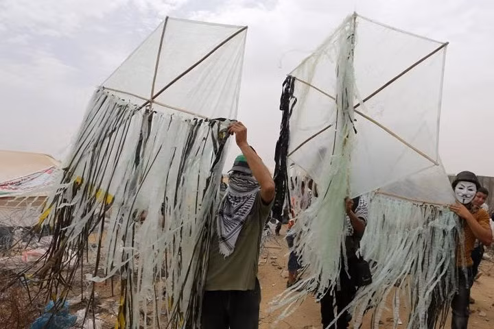 Người Palestine chuẩn bị châm lửa cho các con diều sắp thả theo gió bay sang Israel trong đợt đụng độ vào đầu tháng 5.