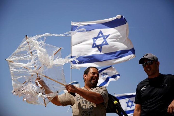 Một nam giới Israel cầm diều mà ông thu được khi nó bay qua hàng rào biên giới sang bên Israel.