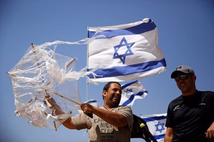 Một nam giới Israel cầm diều mà ông thu được khi nó bay qua hàng rào biên giới sang bên Israel.