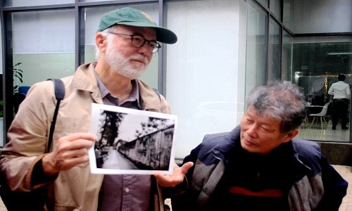 Nhà báo Kennerly với bức ảnh chụp bờ tường trại giam năm xưa. Ảnh: Huỳnh Phan