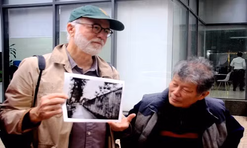 Nhà báo Kennerly với bức ảnh chụp bờ tường trại giam năm xưa. Ảnh: Huỳnh Phan