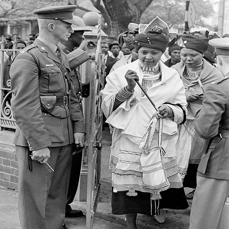 Bà Winnie mặc bộ váy truyền thống khi tham dự phiên tòa xét xử chồng của bà, ông Nelson, ở Pretoria năm 1962. Trong phiên tòa này, ông Nelson đã được tuyên bố vô tội trước cáo buộc xúi giục và rời khỏi Nam Phi một cách bất hợp pháp. Ảnh: AP.