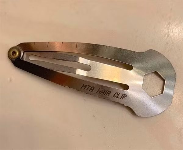 chiếc kẹp tóc đa dụng cụ có một đầu phẳng nhỏ, giống như đinh vít ở phía bên kia khi bạn mở nó.