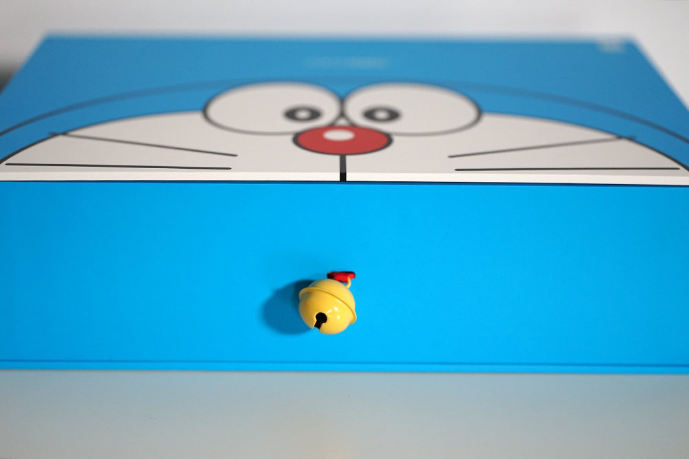 Vỏ hộp của Mi 10 Youth Edition với tông màu chủ đạo là màu xanh, bên ngoài có in hình khuôn mặt của mèo máy Doraemon. Phía cạnh bên là chiếc chuông màu vàng đặc trưng dùng để mở hộp.