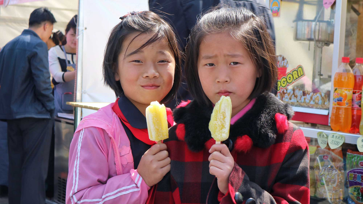 Hai bé gái đang cầm que kem trên tay nhìn về phía ống kính của vị khách nước ngoài này.