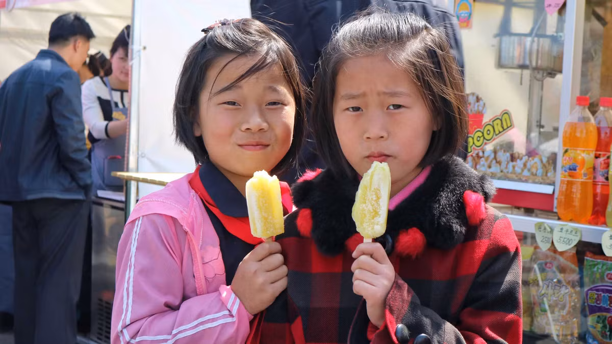 Hai bé gái đang cầm que kem trên tay nhìn về phía ống kính của vị khách nước ngoài này.
