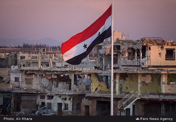 Các lực lượng quân đội Syria đã giành lại quyền kiểm soát nhiều khu vực tại tỉnh Daraa từ tay các phần tử khủng bố. Ảnh: Lá cờ Syria tung bay trước những tòa nhà đổ nát ở Daraa.