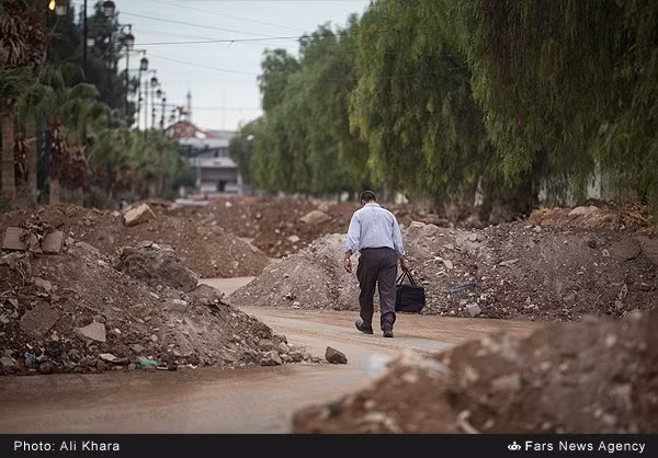 Người đàn ông đi bộ qua con đường với những mô đất ngổn ngang hai bên.