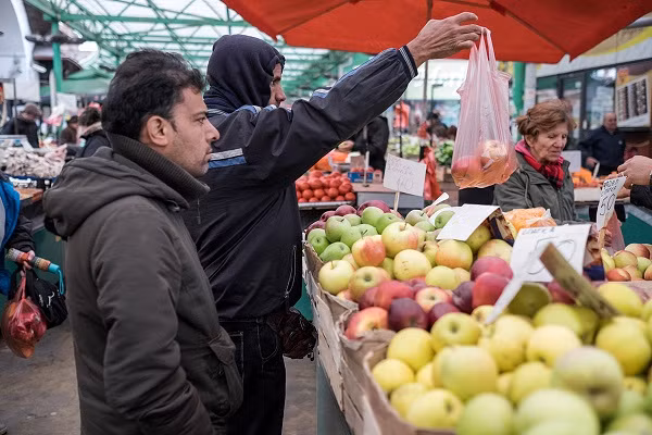 Người đàn ông mua hoa quả trong một khu chợ gần trung tâm hỗ trợ người tị nạn Miksaliste.