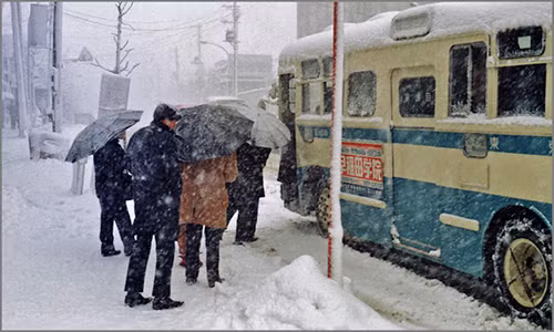 Mọi người lên xe buýt giữa trời tuyết rơi trắng xóa ở Tokyo hàng chục năm về trước.