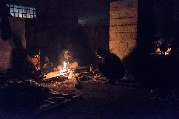 Một số người đốt lửa sưởi ấm trong một nhà kho bỏ hoang phía sau nhà ga trung tâm ở Belgrade. (Nguồn ảnh: Al Jazeera).