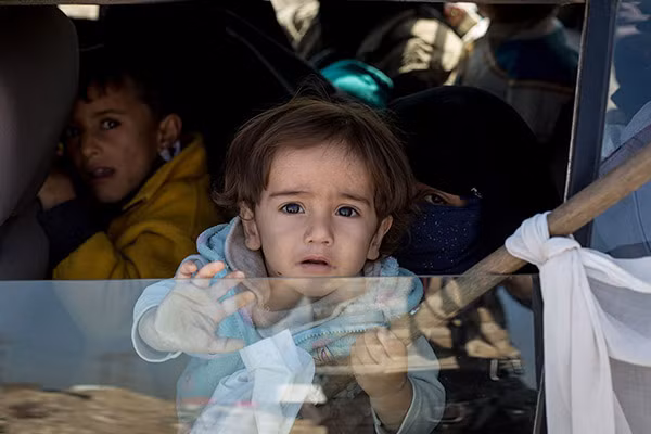 Một em nhỏ Iraq cầm lá cờ trắng trên tay khi ngồi trên ô tô tới khu trại tị nạn ở Mosul.