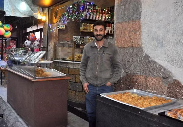 Người đàn ông Syria mỉm cười tại một cửa hàng ở Qodsiyeh. Ảnh: FNA.