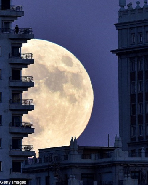 Siêu trăng thế kỷ “lấp ló” phía sau một tòa nhà ở Madrid, Bồ Đào Nha. Ảnh: Getty Images.