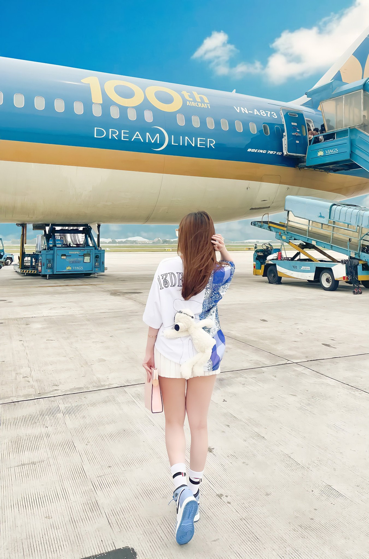 Ra sân bay, cô giáo hot girl chọn trang phục rộng rãi, kết hợp mặc chân váy xòe, ngắn trên đầu gối trông cực dễ thương.